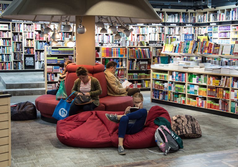 A welcoming library space with people relaxing and reading on comfortable seating.