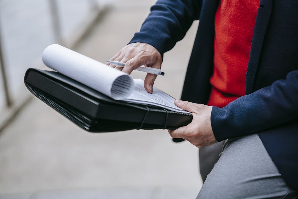 Professional introvert sales representative conducting detailed document review outdoors, demonstrating flexible work environment and focused attention to client materials and strategic planning