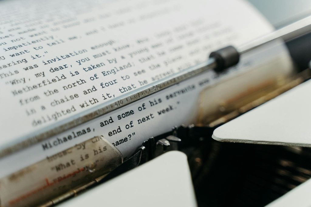 Close-up of a vintage typewriter typing manuscript pages in a classic style.