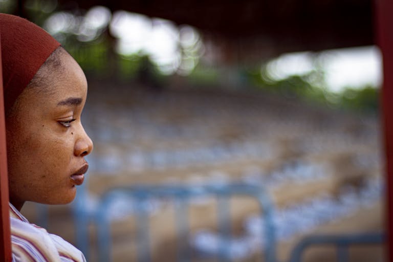 Contemplative portrait of a woman with blurred background outdoors.
