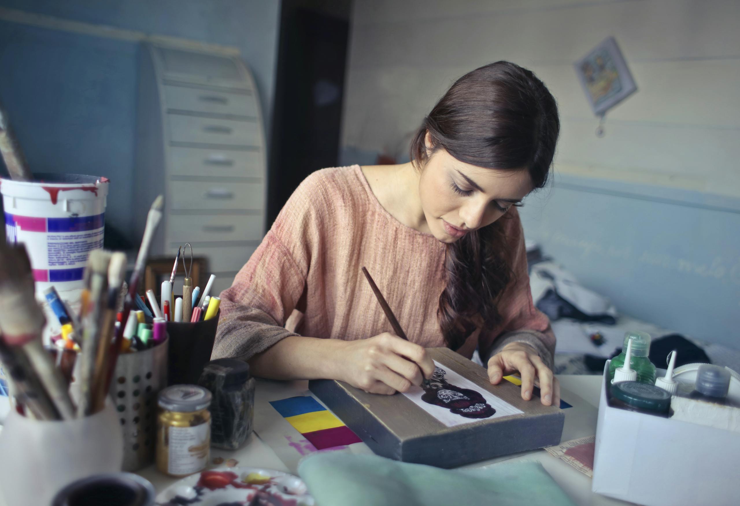 Introverted artist deeply focused on painting in a quiet creative studio filled with natural light