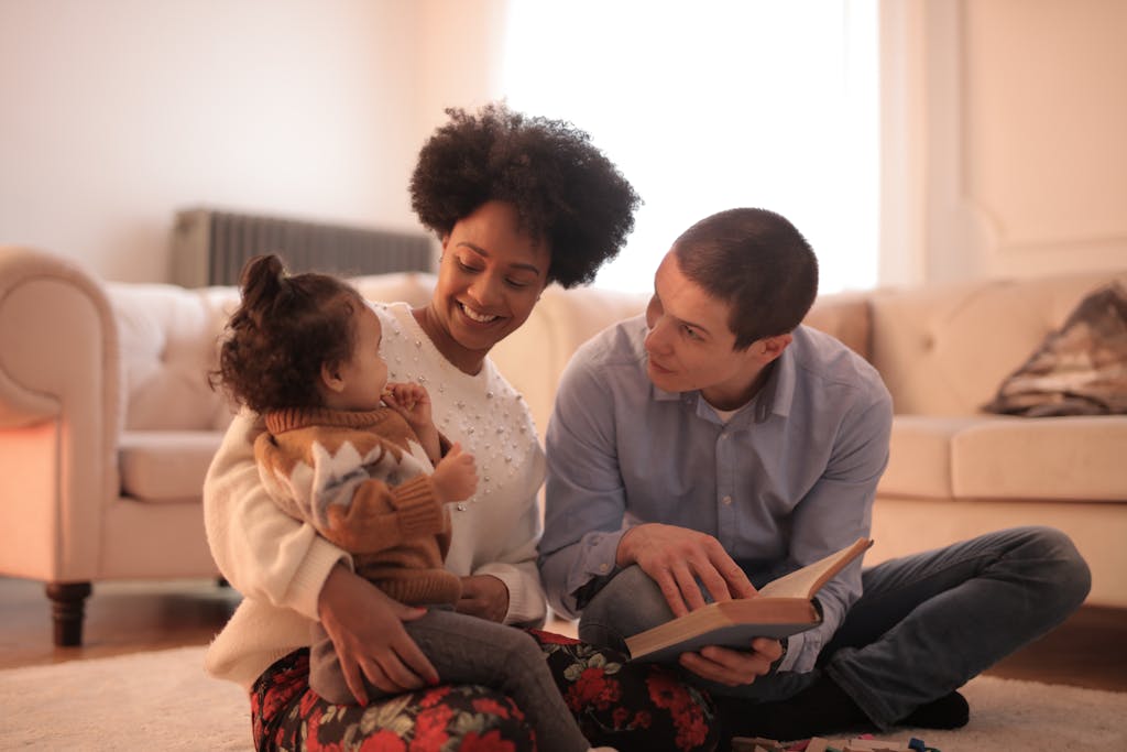 Loving parents reading with cheerful toddler in cozy living room embracing family time and quiet connection