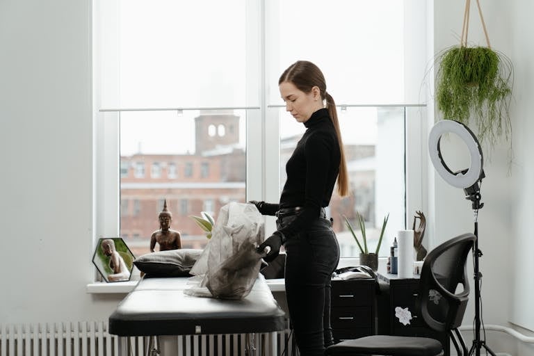 Tattoo artist in a sunlit studio setting up equipment near a large window.