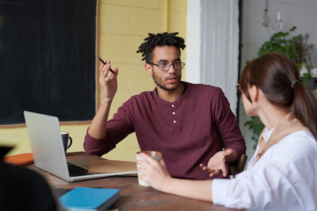 Two colleagues engaged in a collaborative discussion during a team meeting at the office.