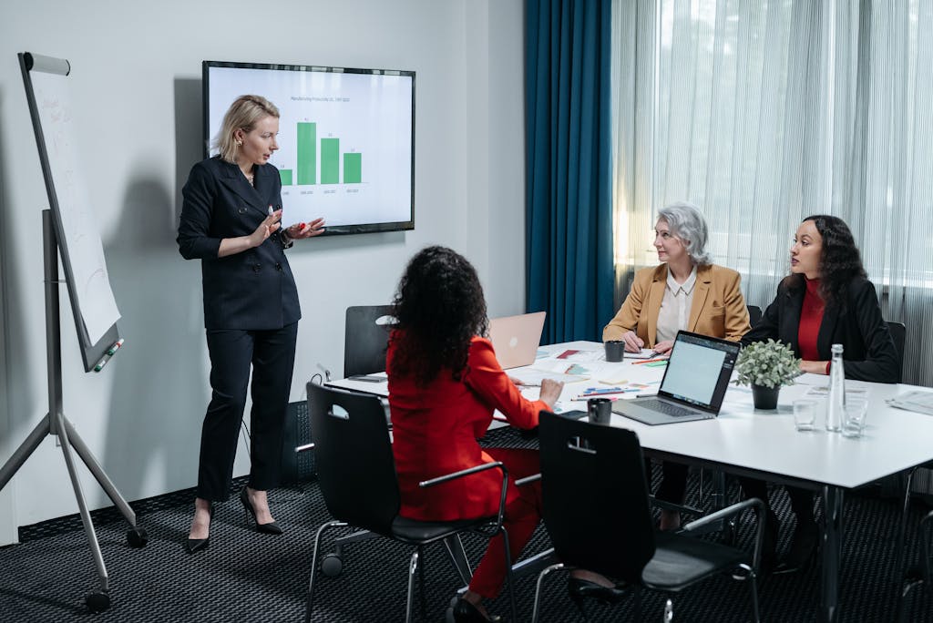 A group of professional women engaged in a business presentation in a modern conference room.