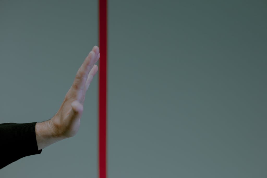 Speak up to intimidating people. Close-up of a man's hand gesturing stop in front of a vertical red line, concept of boundary.