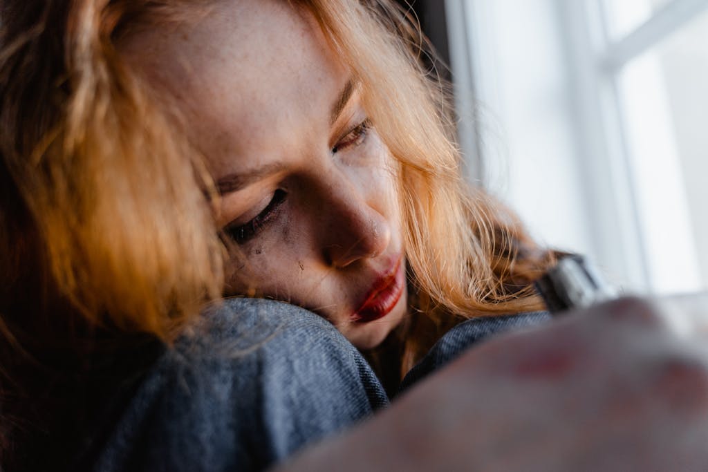 Close-up of a woman with red hair in a thoughtful and emotional moment indoors.