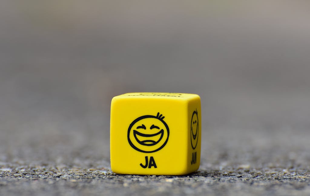 Close-up of a yellow dice featuring a smiley face emoticon symbolizing happiness and fun.