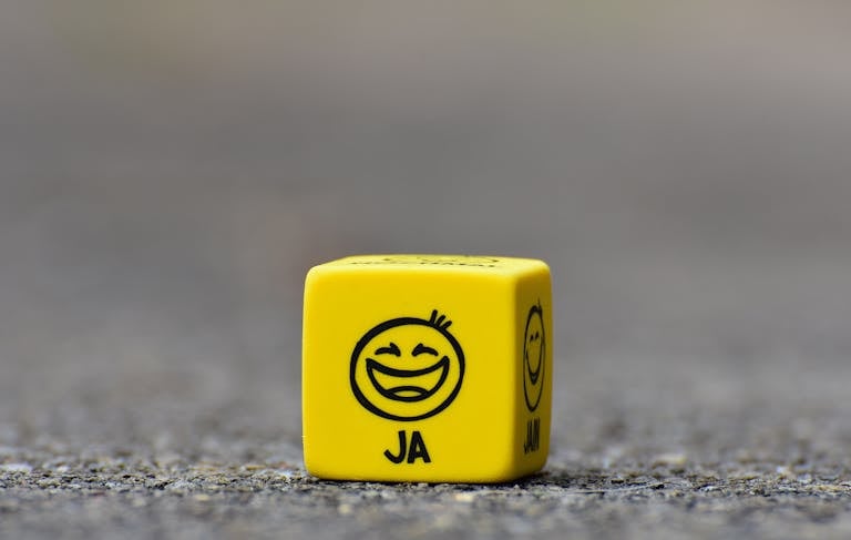 Close-up of a yellow dice featuring a smiley face emoticon symbolizing happiness and fun.