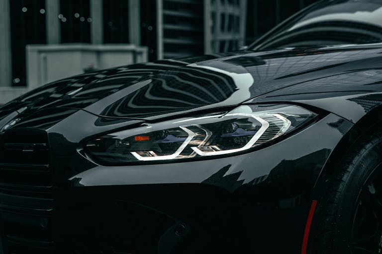 Close-up shot of a black BMW M3 headlight in downtown Chicago, showcasing modern design.