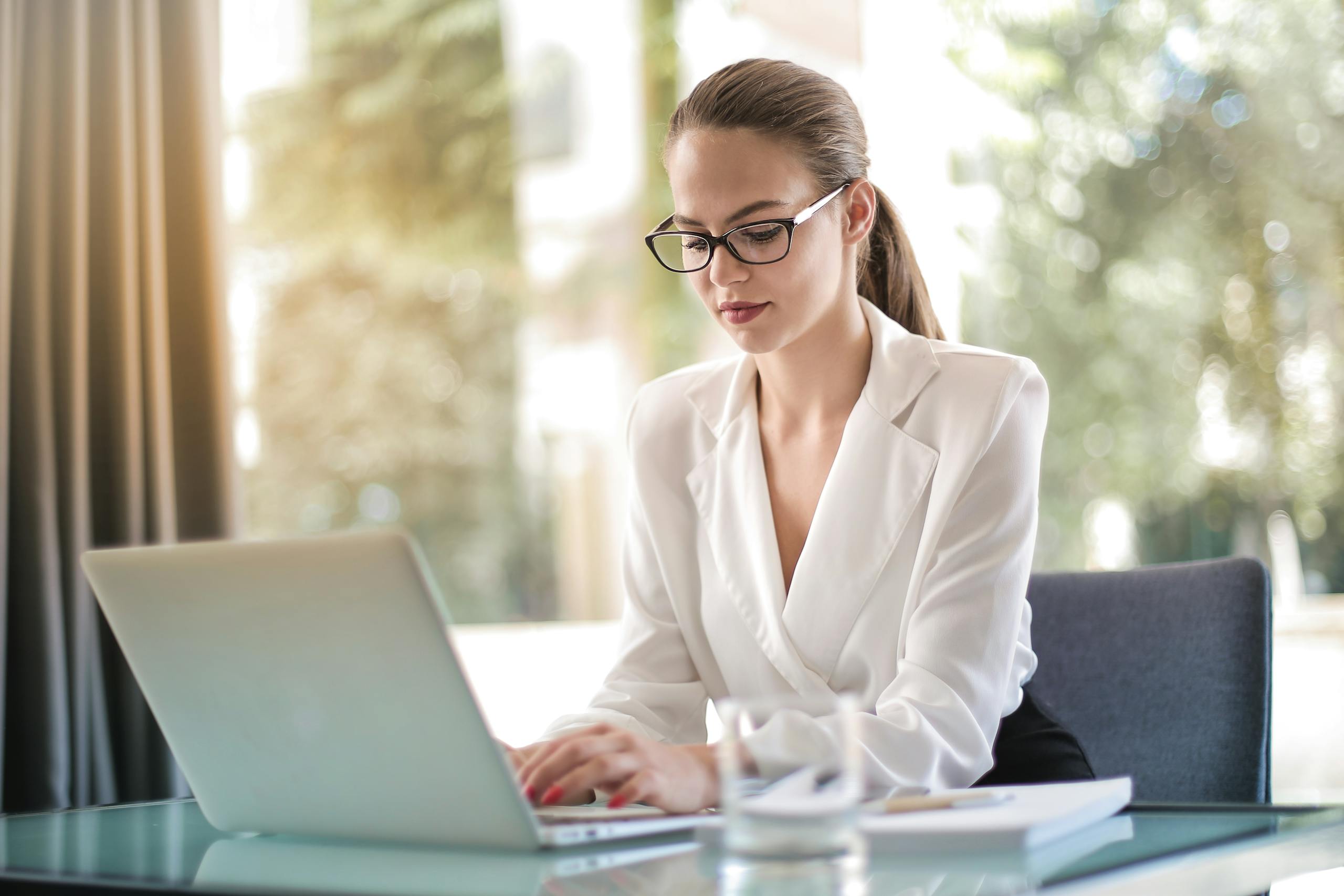 Professional woman focused on crafting thoughtful content at her desk, demonstrating the power of written communication for client attraction