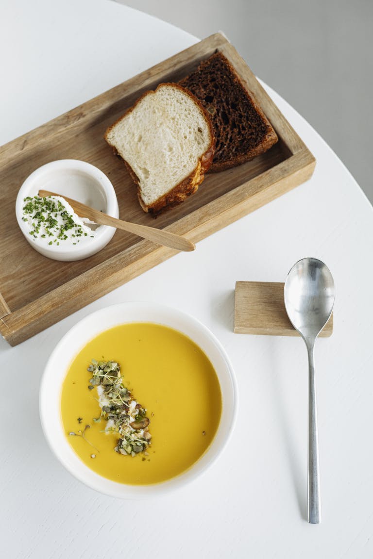 Delicious pumpkin soup served with fresh bread and a creamy dip, perfect for gourmet dining.