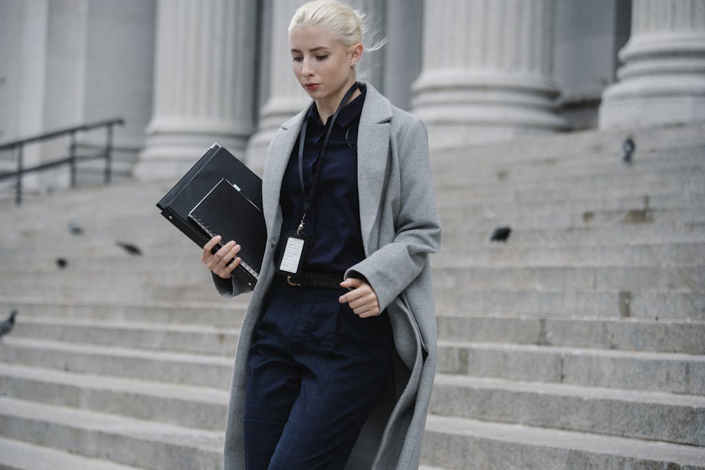 Introvert lawyers make up 60% of all lawyers. Professional woman in formal attire walking down courthouse steps holding folders outdoors.