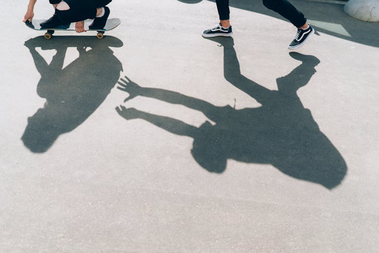 Silhouette of a skateboarder and running person casting a dramatic shadow.