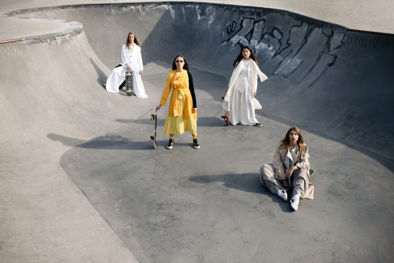 Stylish women in trendy outfits posing with skateboards in an urban skate park.