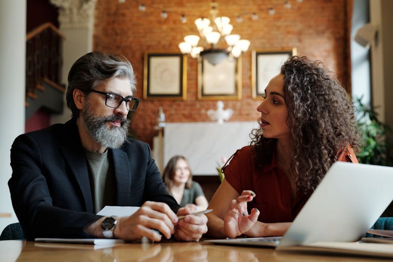 Two business professionals engaging in a strategic discussion with a laptop at a modern office.