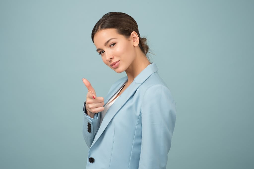 ENTJ leadership failures. A young woman in a blue suit exhibits confidence with a relaxed pose against a blue background.