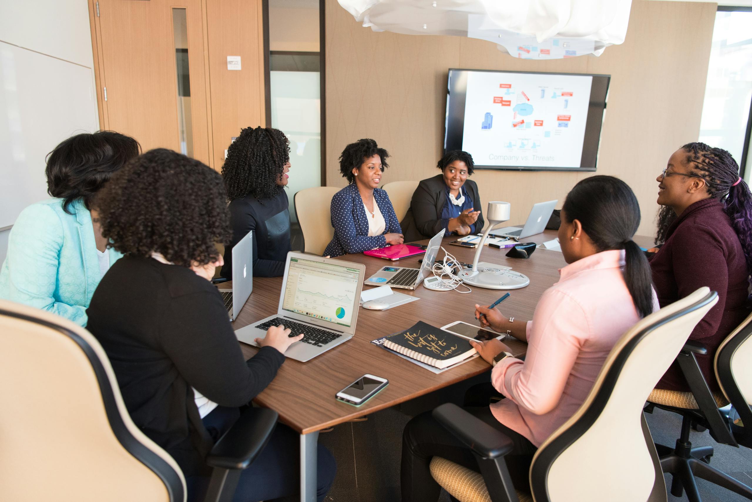 Team meeting in progress with diverse professionals around a conference table, one person listening thoughtfully