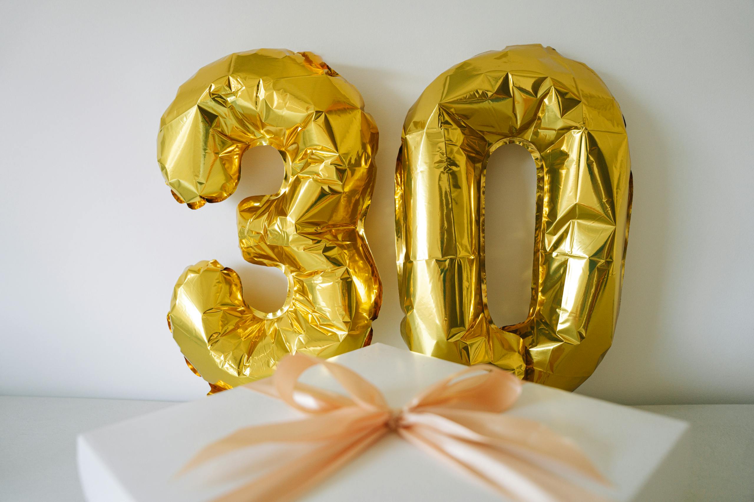 Golden 30 balloon with a wrapped gift box for a 30th celebration or birthday.