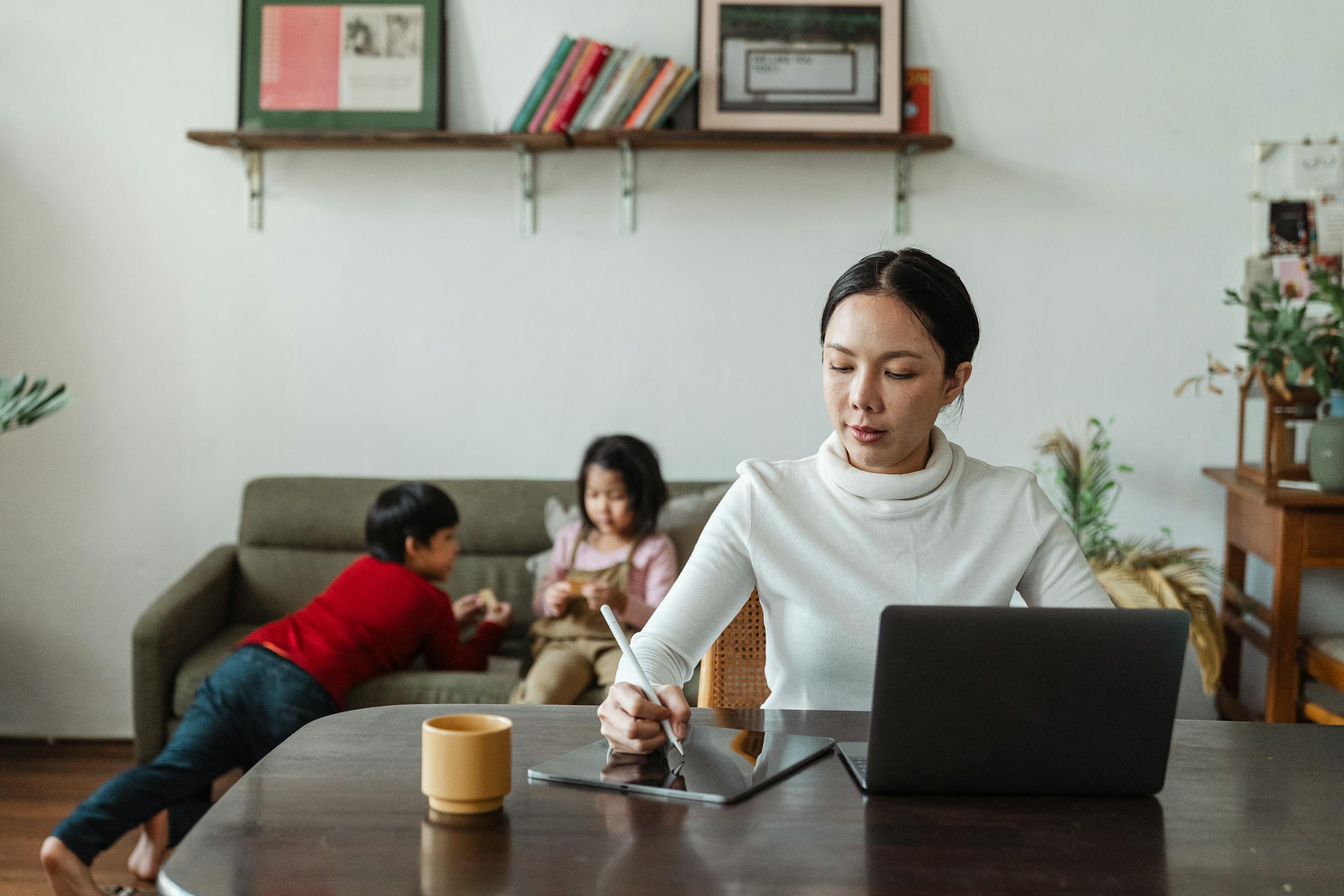 Mother on laptop while child plays nearby, illustrating how introvert parents can integrate friendship into family life