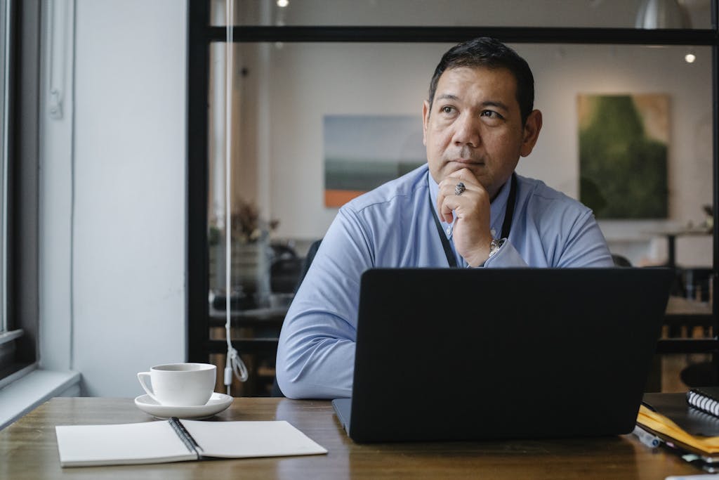 Introvert professional sitting alone at desk contemplating mental health disclosure decision at work