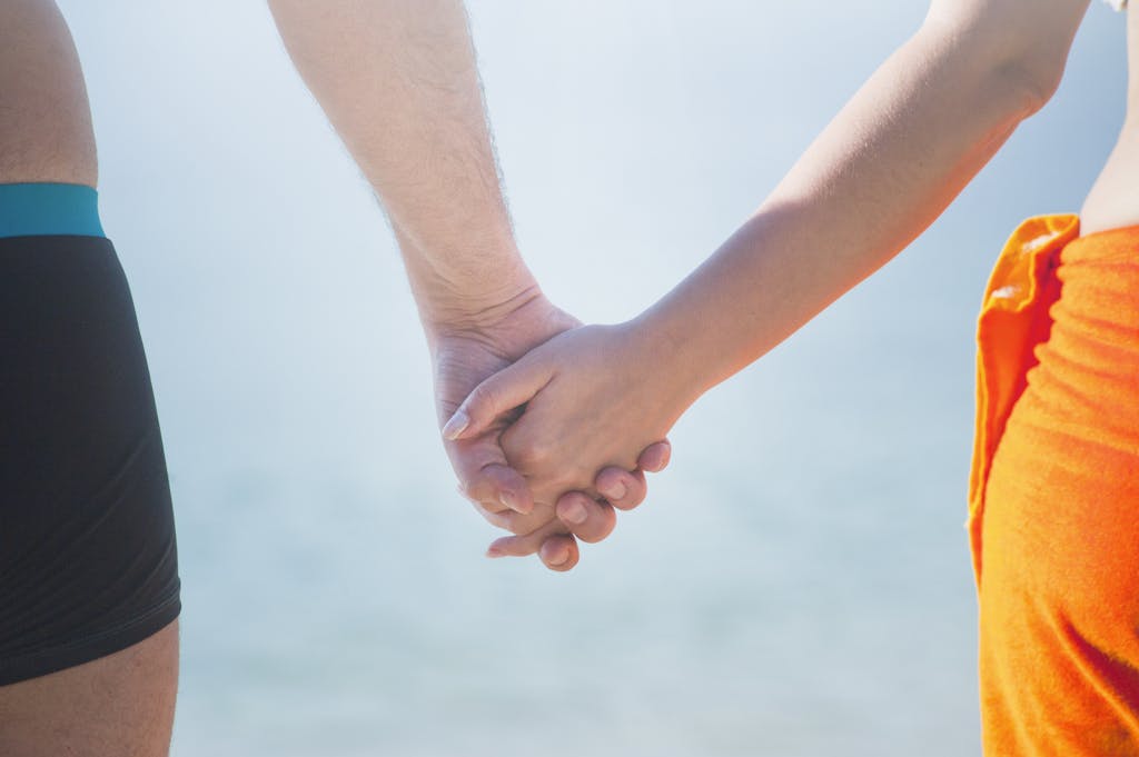 A close-up of a couple holding hands at the beach, symbolizing unity and togetherness