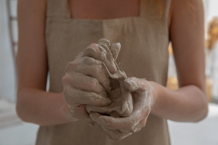 A craftswoman kneading clay in an indoor workshop, showcasing detailed craftsmanship.