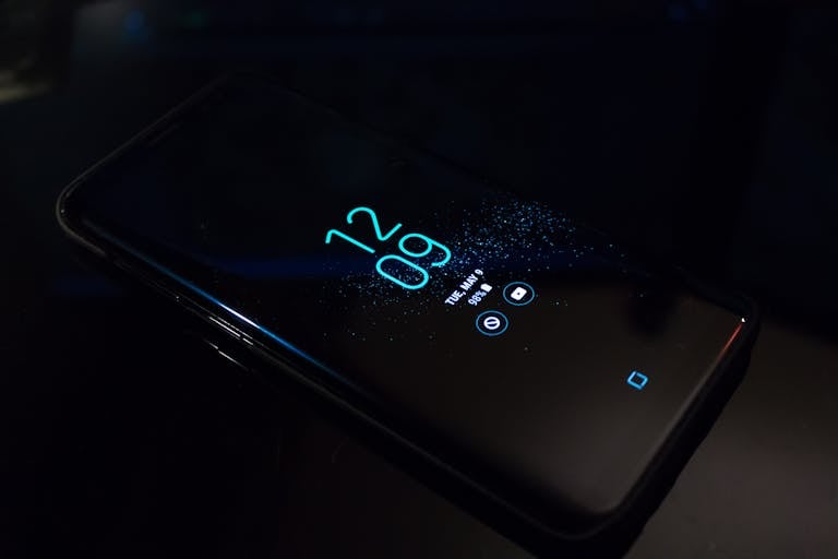 Close-up of a smartphone in the dark displaying digital clock and notifications.