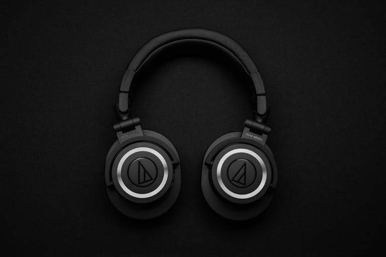 Close-up of black over-ear headphones on a black background, showcasing modern design.