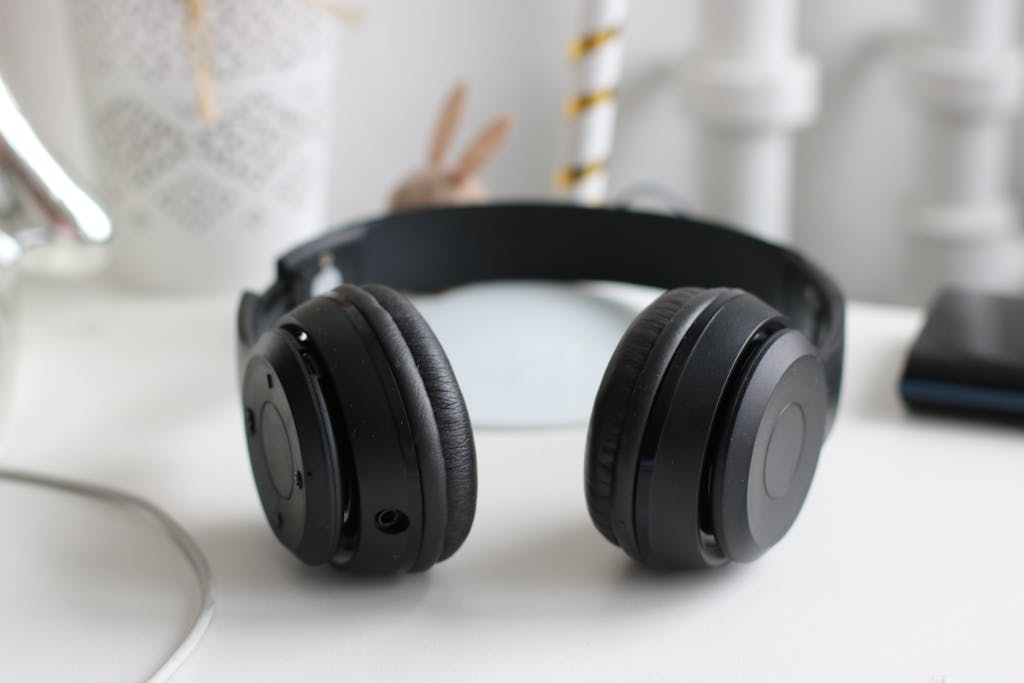 Close-up of black wireless headphones on a white desk in a modern setting.
