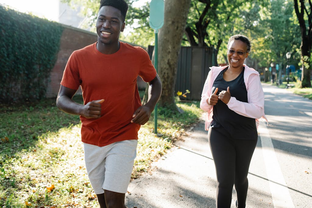 Happy couple enjoys jogging in a sunny park, embracing a healthy lifestyle.