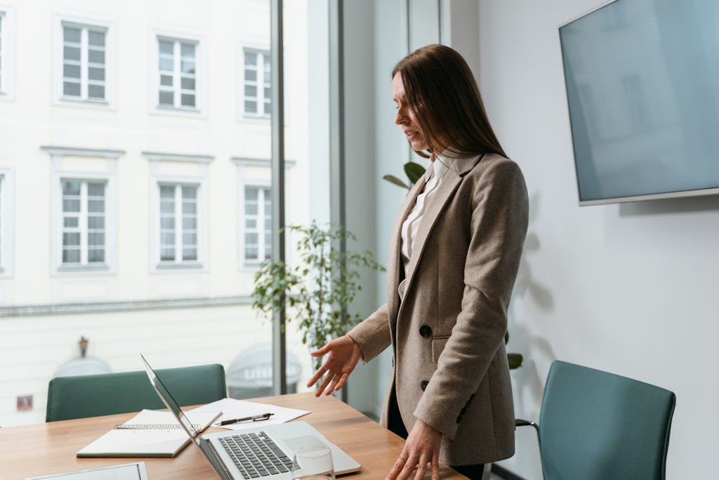 Professional woman in an office setting working on a laptop near a window