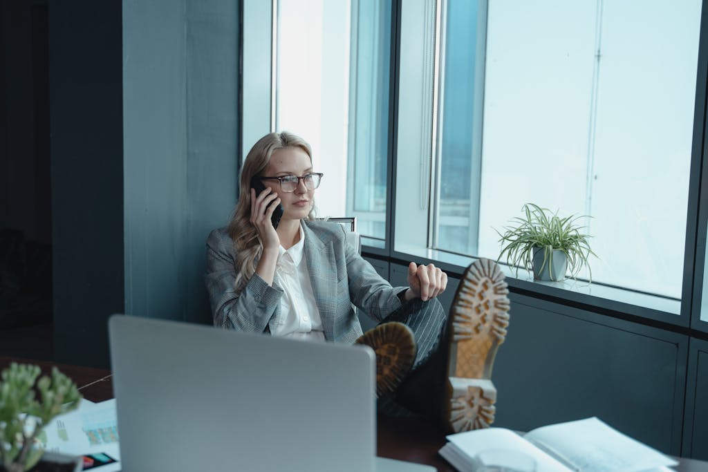 Professional woman in office setting, relaxed yet focused, making a call.