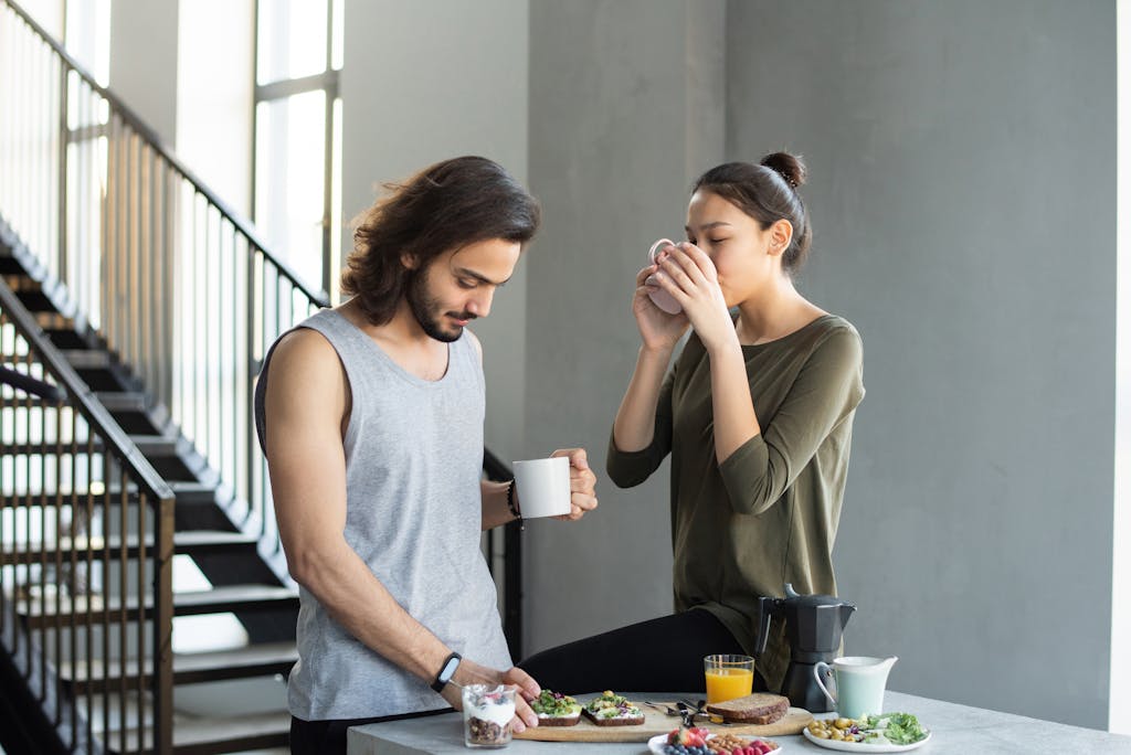 A couple enjoying a cozy breakfast with coffee and juice in their modern home kitchen.
