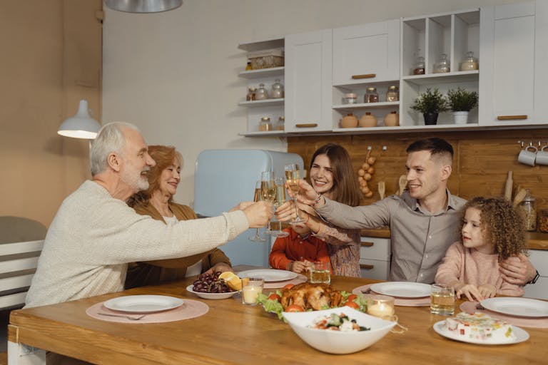 A joyful family toasting at a dinner table indoors, celebrating a special occasion.