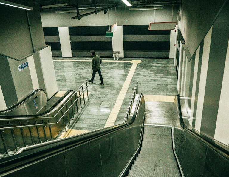 A man walks in an empty İstanbul subway station with visible escalators and modern design.