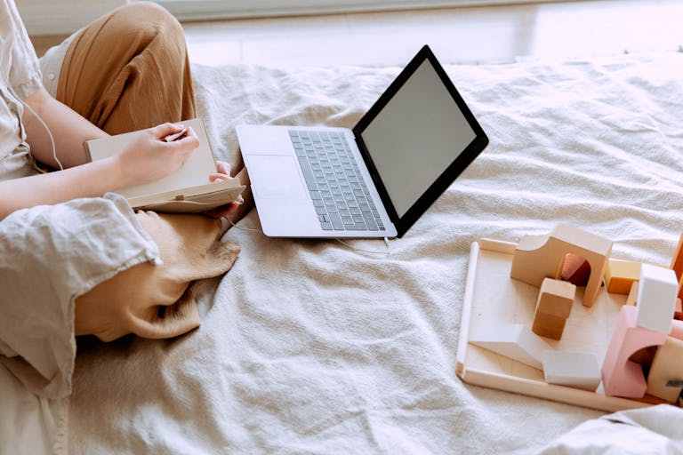 Adult woman working on a laptop while taking notes, showcasing a comfortable home office setting.
