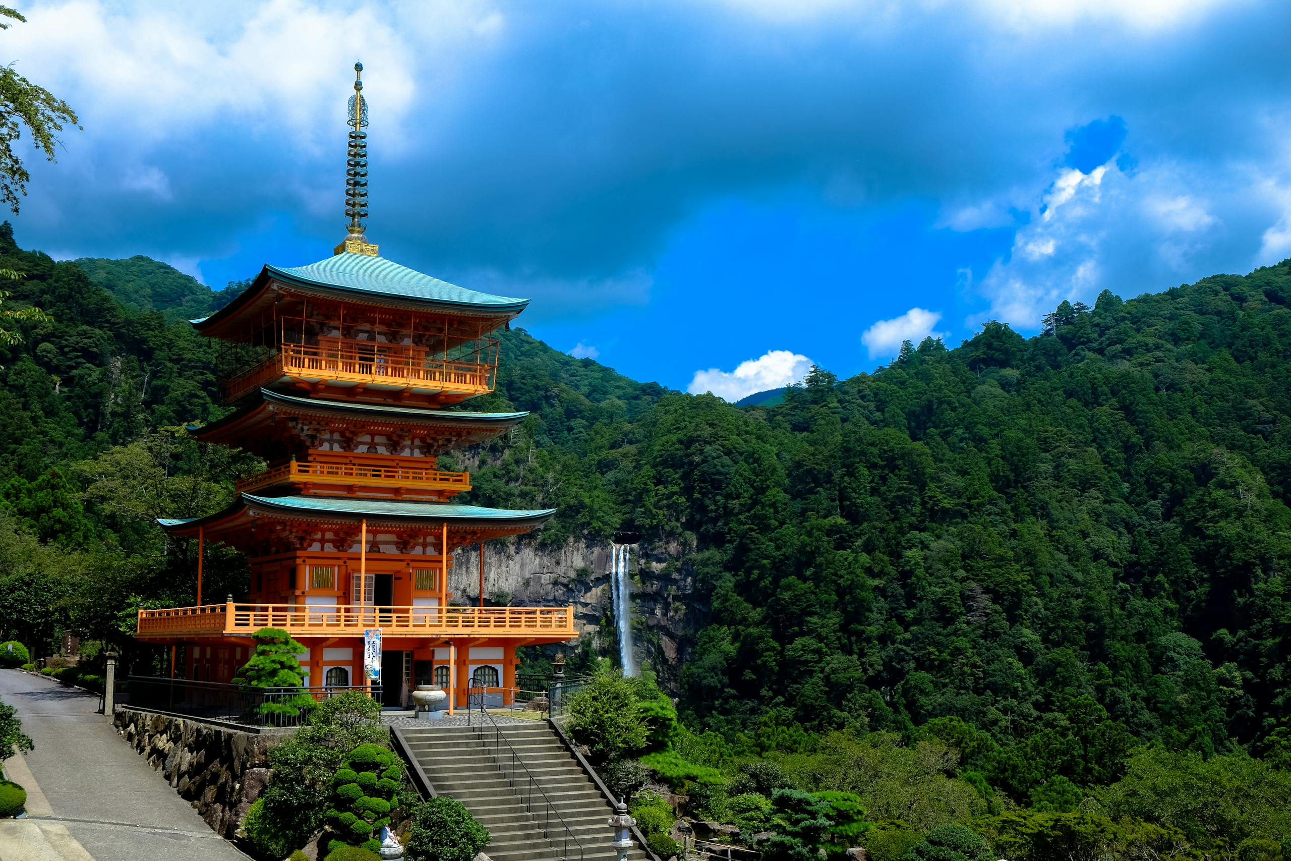 Beautiful view of Kumano Nachi Taisha with a pagoda surrounded by lush green mountains and a waterfall.