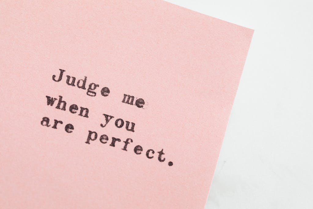 Close-up of an inspirational quote on pink paper, offering a message of judgment and perfection.