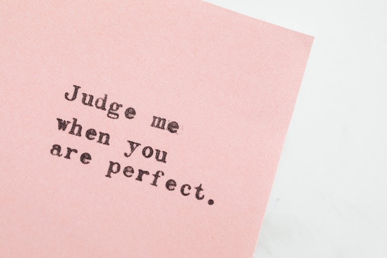 Close-up of an inspirational quote on pink paper, offering a message of judgment and perfection.