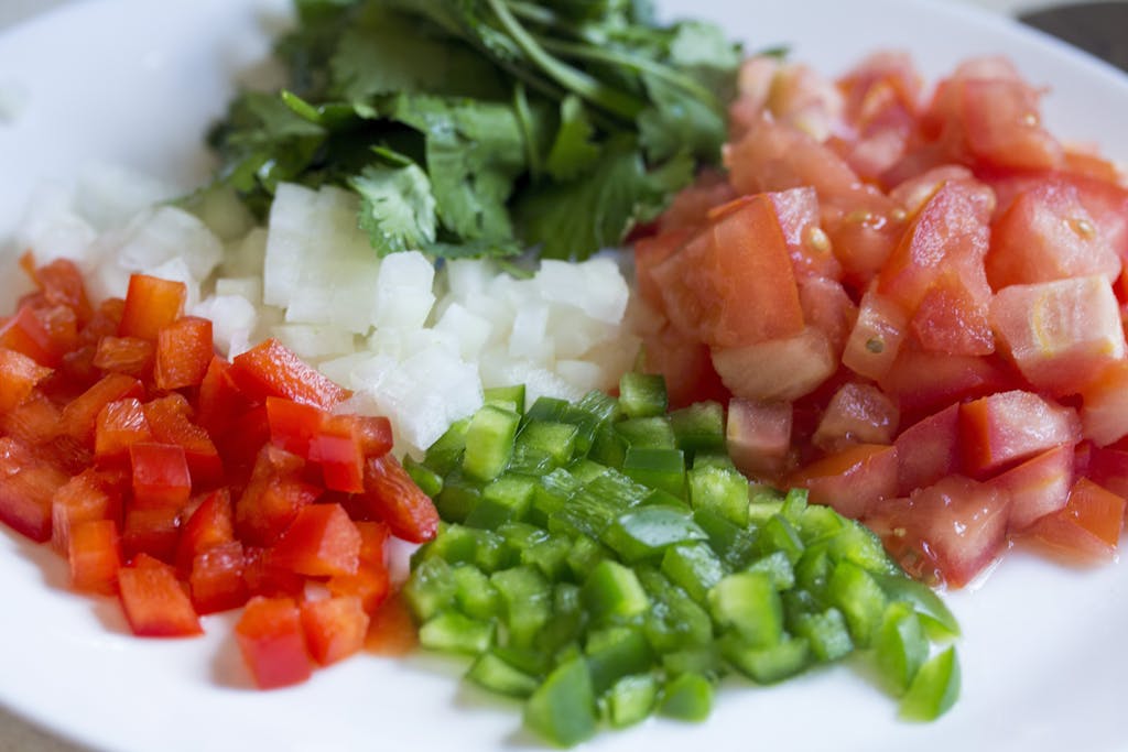 Colorful diced vegetables on a plate, perfect for healthy cooking and meal prep.