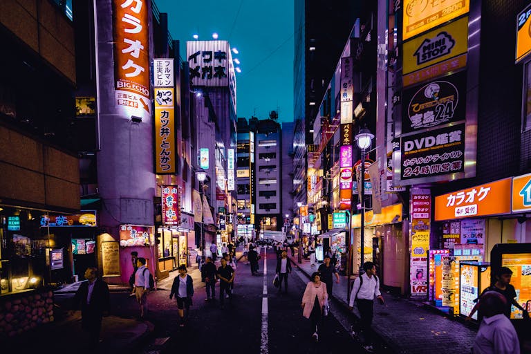 Explore the lively streets of Shinjuku, Tokyo at night with colorful lights and bustling activity.