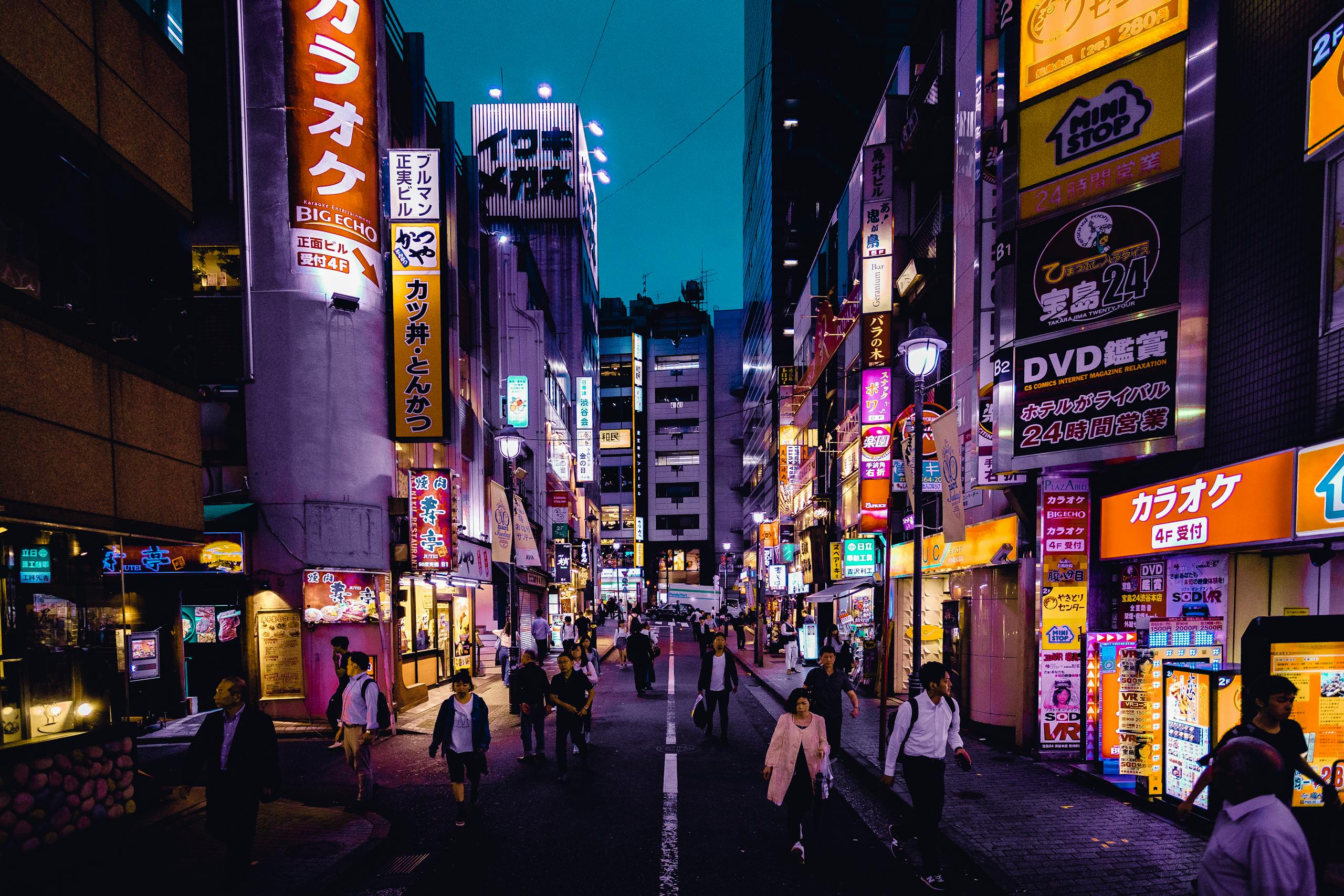 Explore the lively streets of Shinjuku, Tokyo at night with colorful lights and bustling activity.