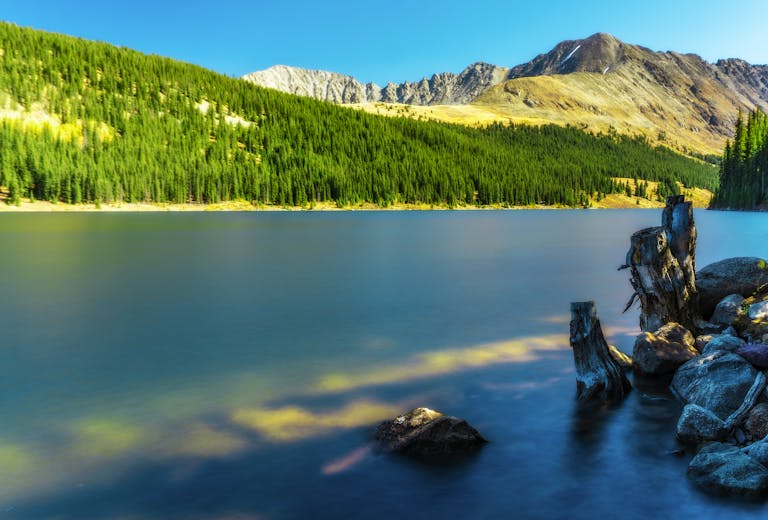 Tranquil mountain lake in Breckenridge, Colorado surrounded by lush forests and scenic landscapes.