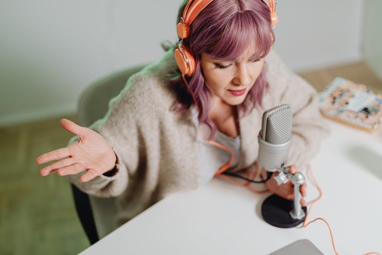 Woman using headphones and microphone to record a podcast indoors.