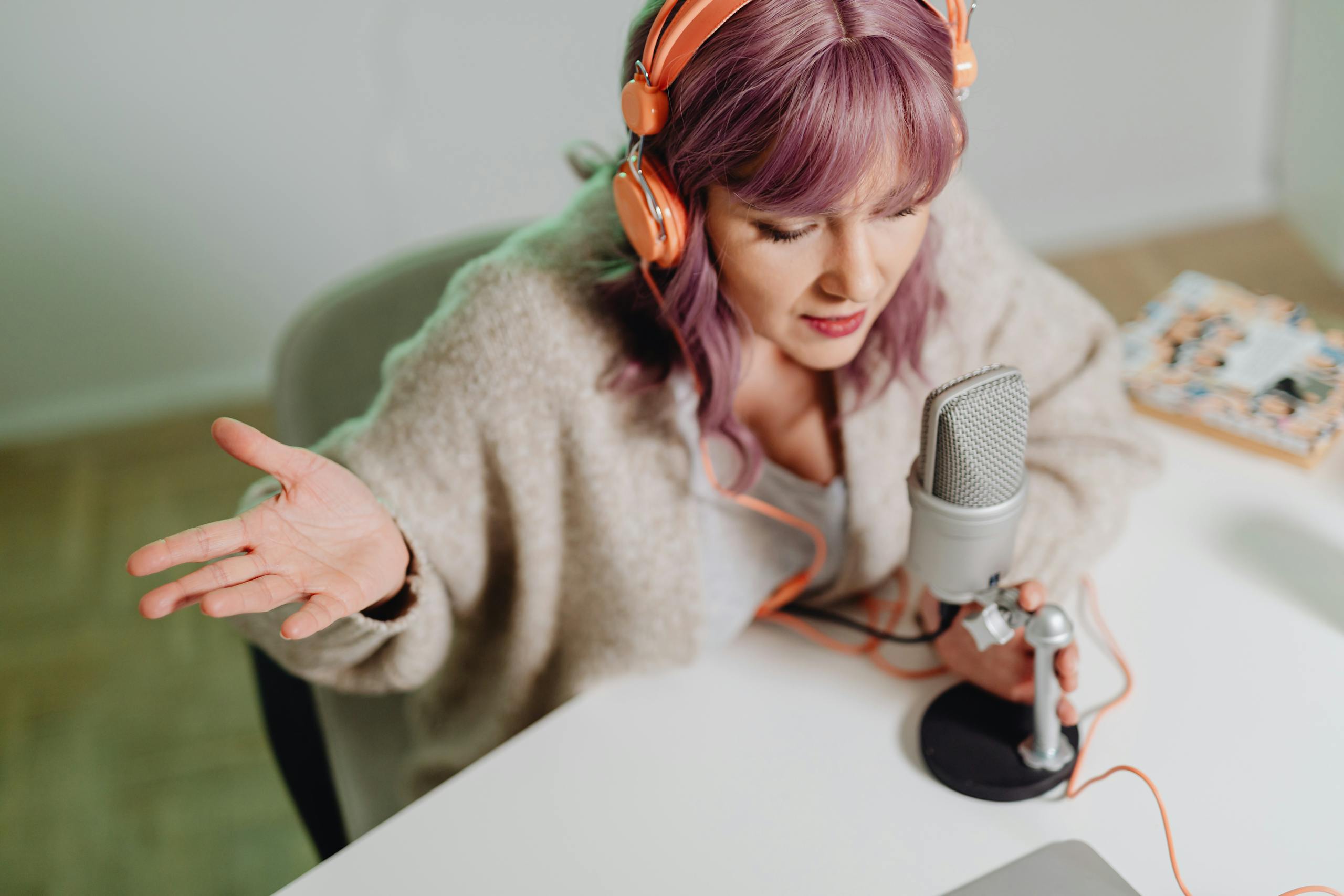 Woman using headphones and microphone to record a podcast indoors.