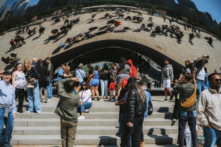 Crowds of people gather at iconic curved architectural landmark on sunny day