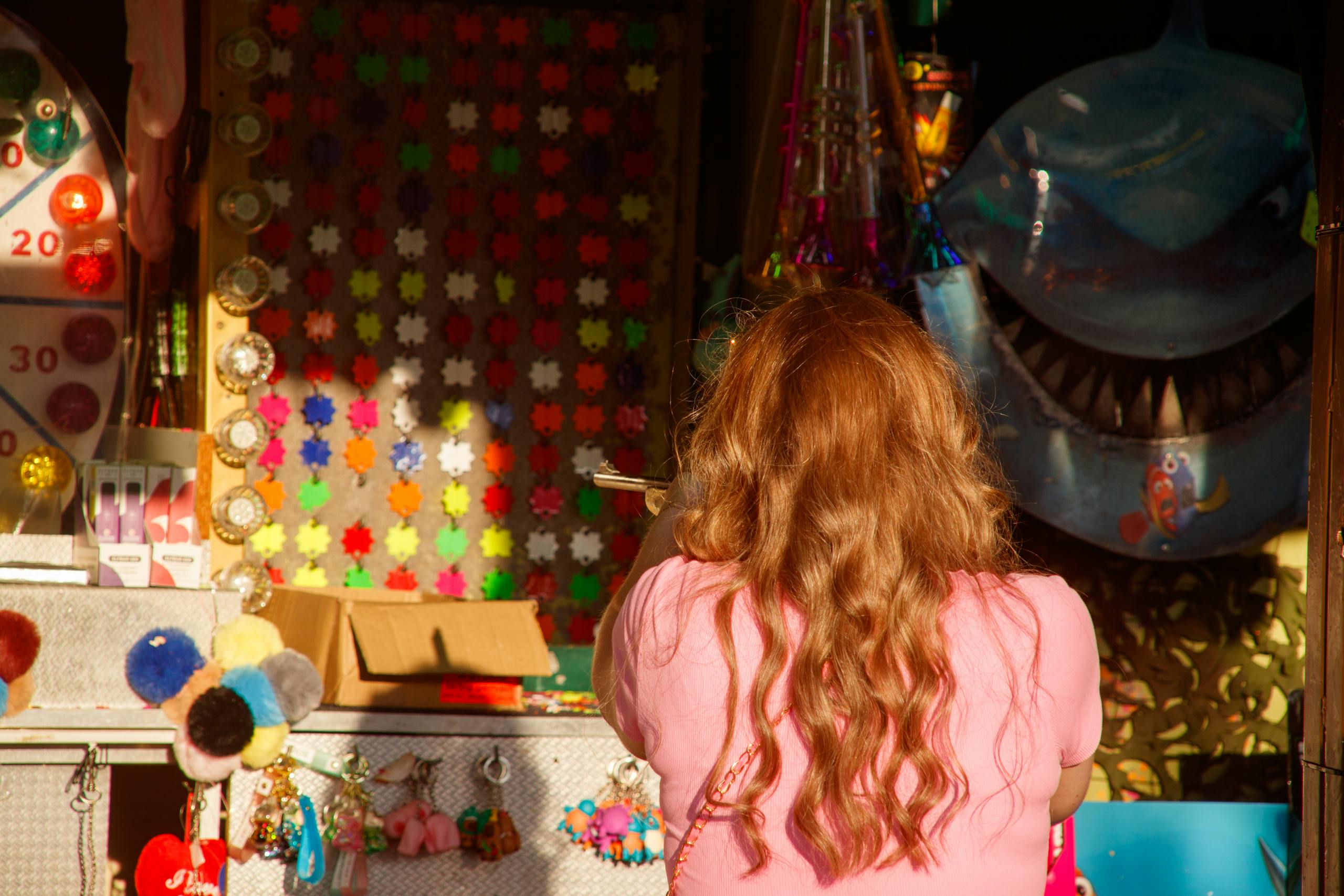 Child with red hair viewing colorful handmade crafts and decorations in shop window