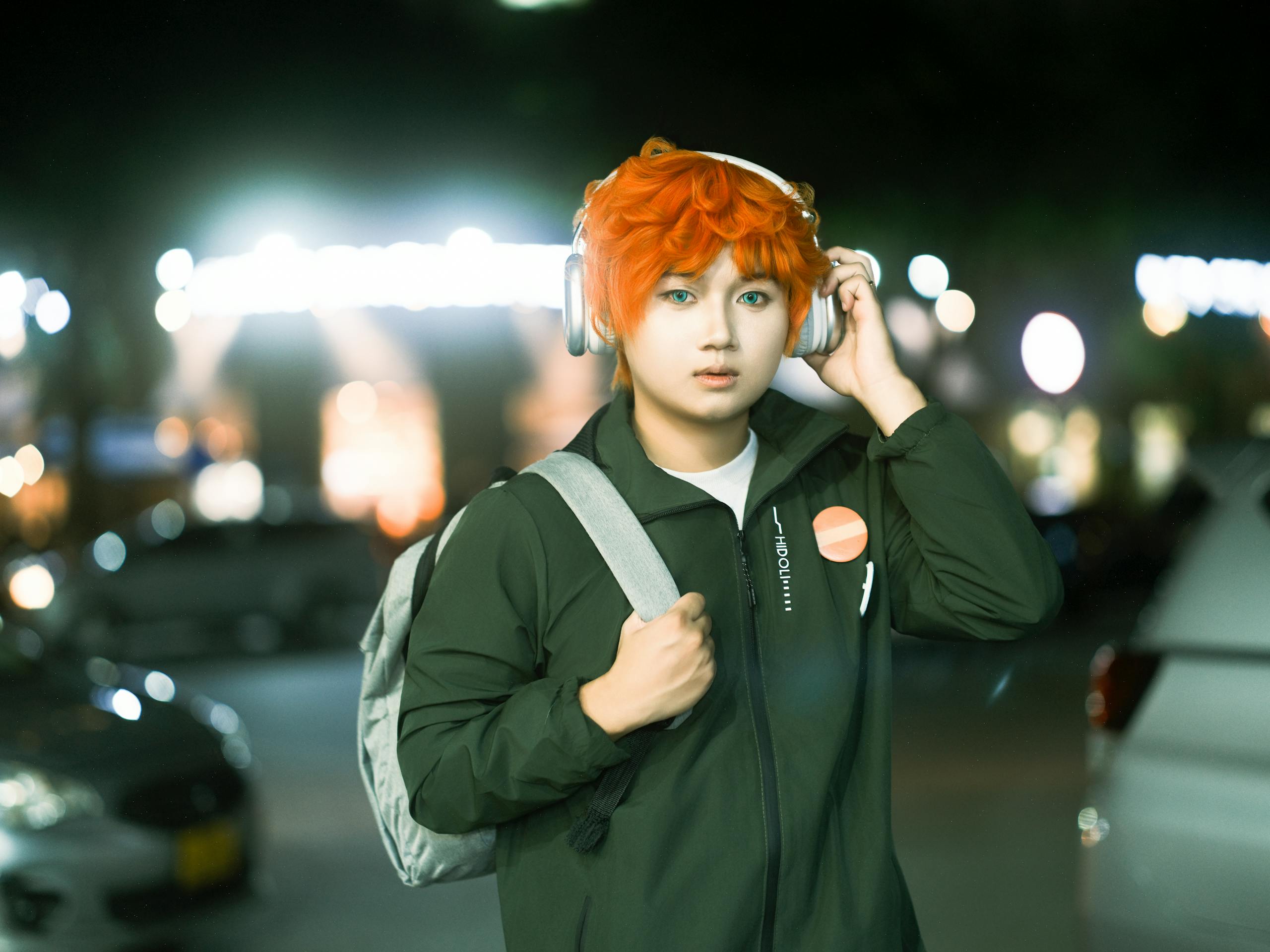 Young person with orange hair wearing headphones, introspective urban night setting