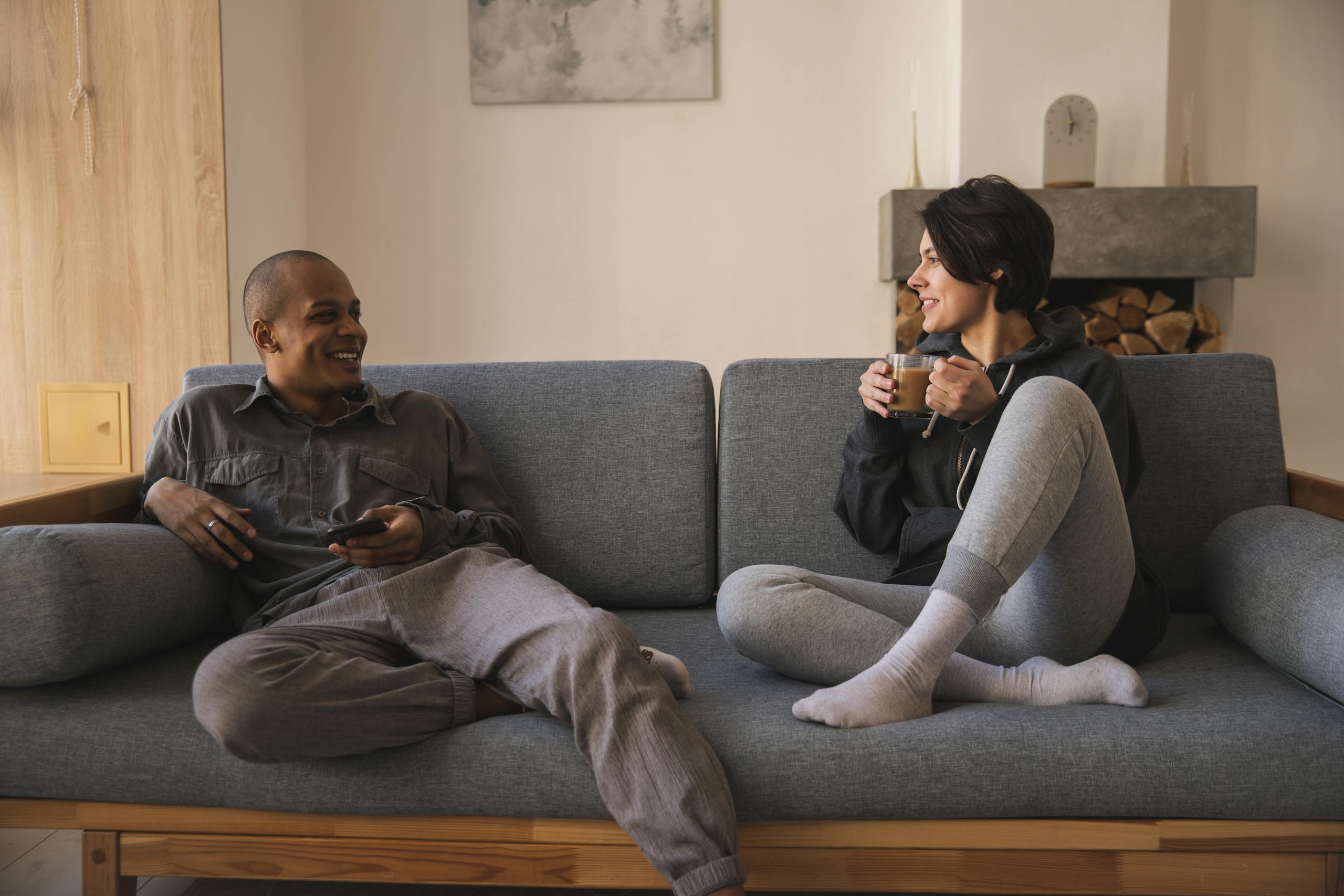 Cheerful couple enjoying coffee and conversation on cozy sofa in modern living room.